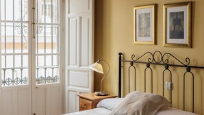 Une chambre à coucher avec un lit, une table de chevet avec une lampe, une porte donnant sur une vue agréable et deux tableaux encadrés accrochés au mur.