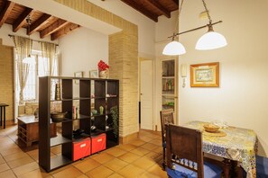 Comedor con mesa, sillas, estantería y lámpara colgante.
