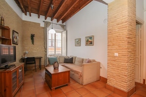 Una sala de estar con sofá, televisión y mueble de madera.