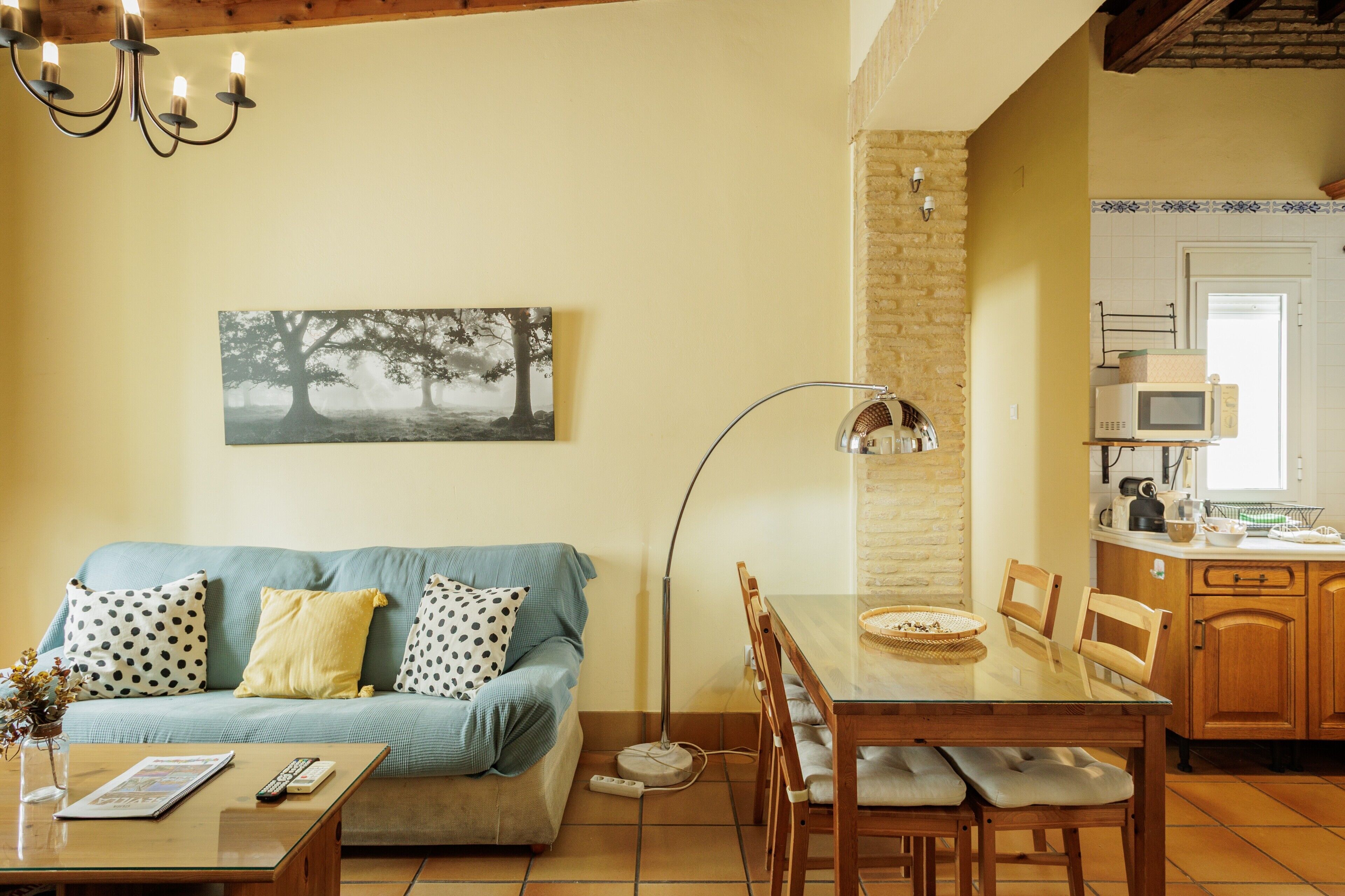 A living room with a sofa, a dining table, and a kitchen area with a microwave.
