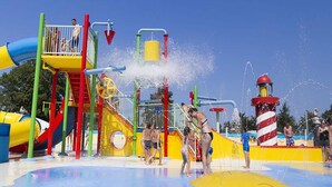 Un parco acquatico con scivoli, area giochi d'acqua e una struttura a forma di faro.