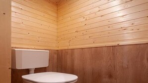 Un bagno piccolo con rivestimenti in legno, un water bianco e serbatoio bianco.