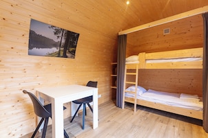 Una habitación tipo cabaña de madera con literas, un escritorio y una silla.