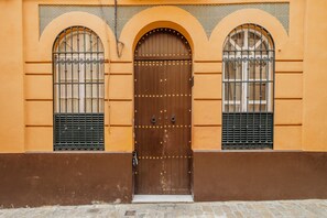 A building with a large wooden door, two arched windows with metal grilles, and a stone-paved ground. - Heart of Seville - Barrio Santa Cruz - WiFi / AC (Sevilla)