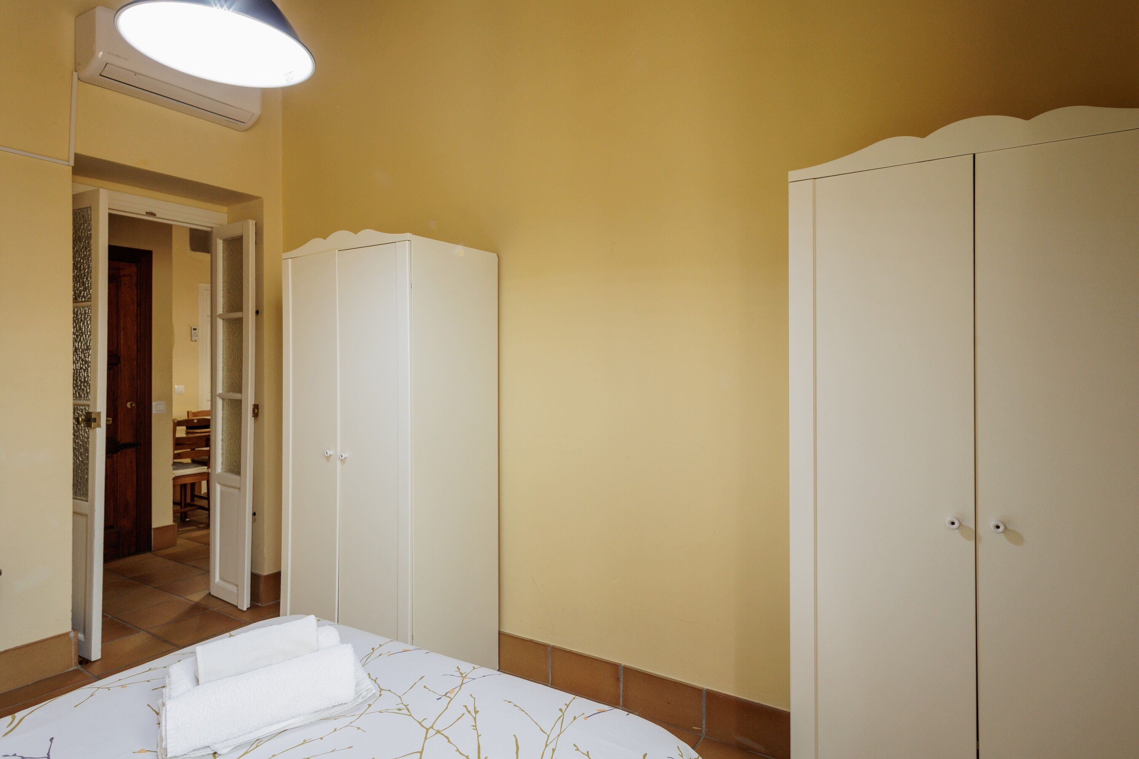 A bedroom with a bed, a wardrobe, and a door leading to a bathroom.