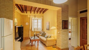A cozy living room with a sofa, a coffee table, a TV, and a fireplace. - Santa Cruz Monumental – Historic Center – WiFi / AC (Sevilla)