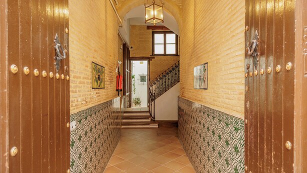 A hallway with patterned walls, a staircase, and a hanging light fixture. - Santa Cruz Monumental – Historic Center – WiFi / AC (Sevilla)