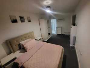 Un dormitorio con cama, mesita de noche, armario, espejo y ventilador de techo.