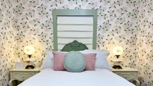 A bedroom with a bed, two bedside tables, a nightstand, a decorative headboard, and wall-mounted lamps. - Mon Sherri - The Cottage (Loxley)