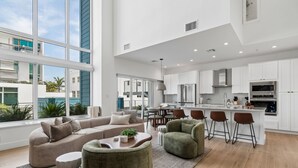 Un espacio moderno y abierto para sala y comedor, con un ventanal grande, un sofá, una mesa de centro y una zona de bar.