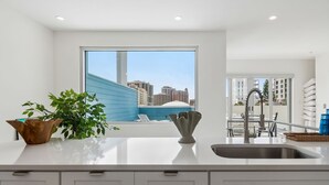 Una cocina moderna con un ventanal grande, un lavamanos y vistas a un paisaje urbano.