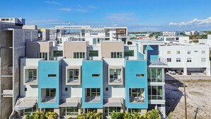 Un moderno edificio residencial de varios pisos con balcones, ventanas grandes y una grúa de construcción al fondo.