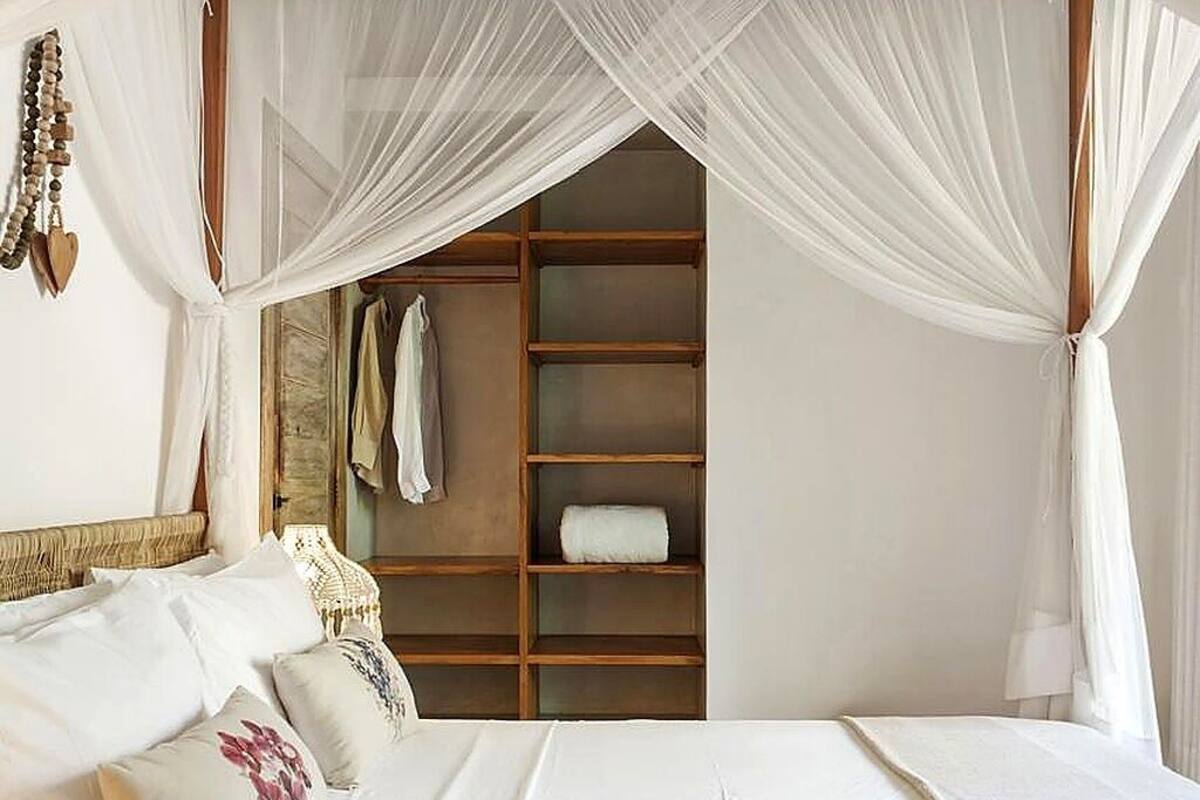 Un dormitorio con cama a dosel, un armario de madera y un collar de cuentas colgante.