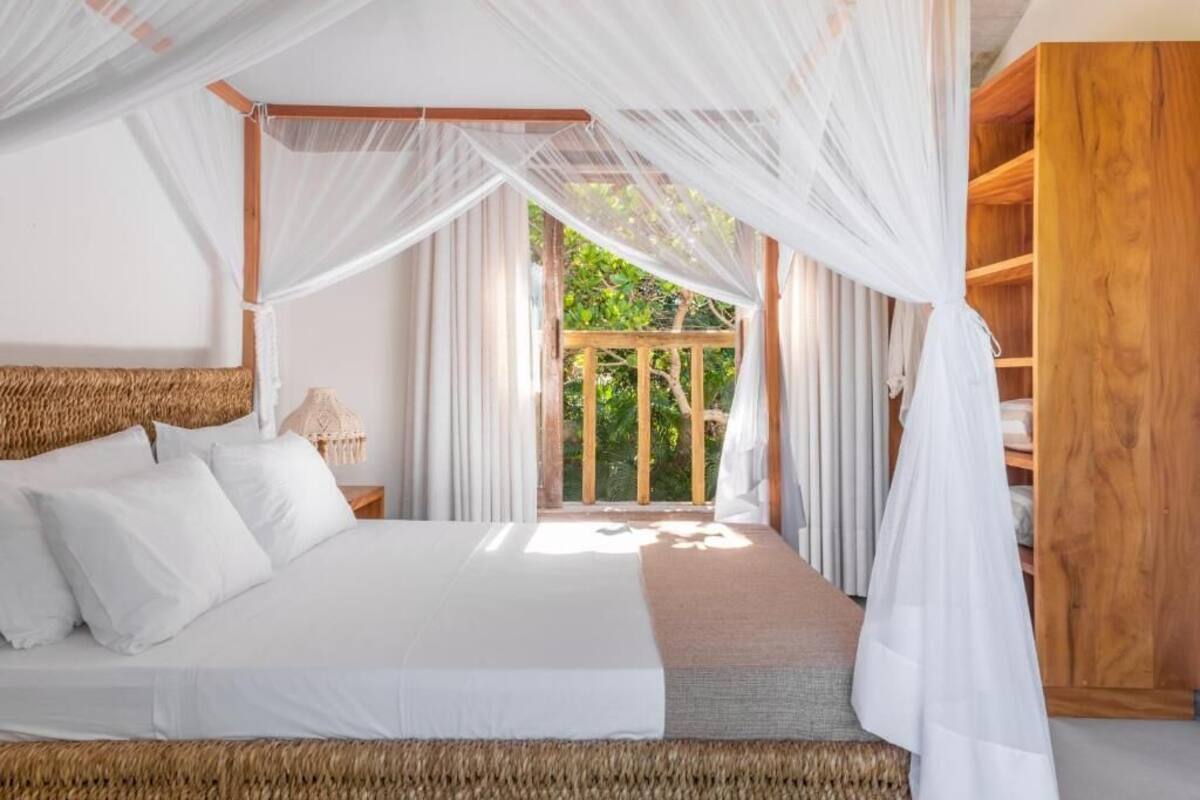 Un dormitorio con cama a dosel, cabecera de madera y vistas al exterior.