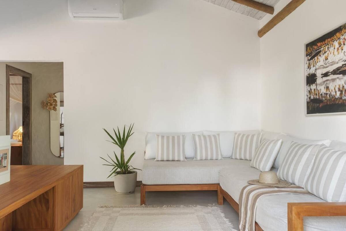 Una sala de estar moderna con un sofá modular, una mesa de centro de madera, una planta en maceta y un cuadro en la pared.