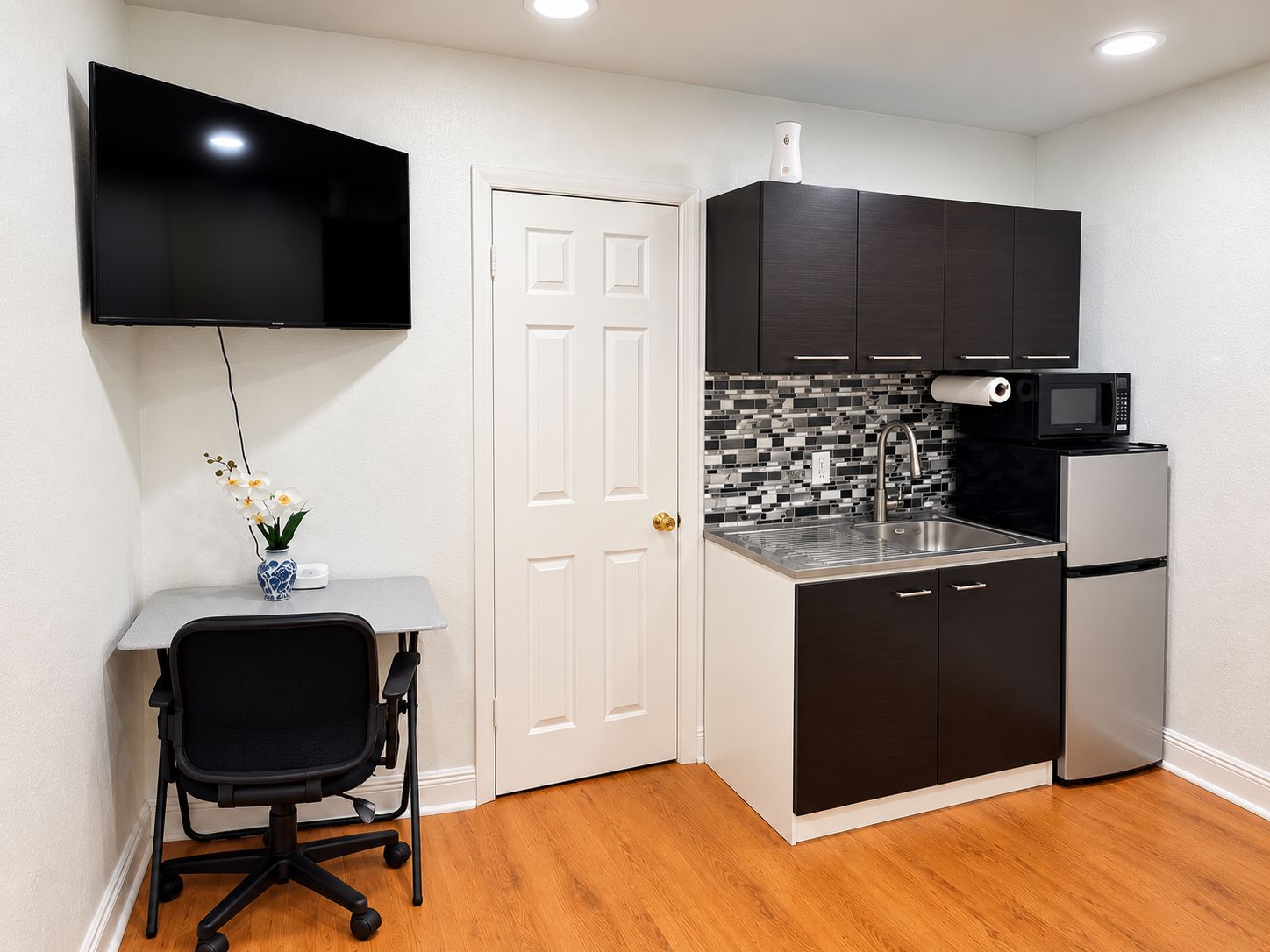 A compact kitchen with a flat-screen TV, a microwave, and a refrigerator.