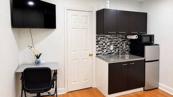 A compact kitchen with a flat-screen TV, a microwave, and a refrigerator.
