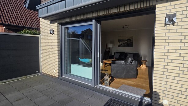 A modern building with a glass door leading to a living area with a sofa and a coffee table.