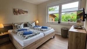 A bedroom with a bed, bedside tables, a lamp, a window with a view, and a painting on the wall.