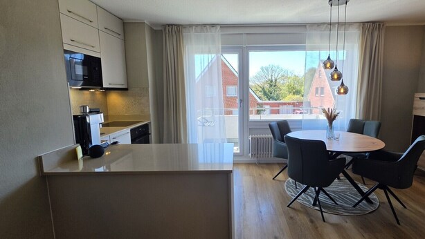 Une cuisine moderne avec un coin repas, une vue sur l’extérieur et une petite table avec des chaises.