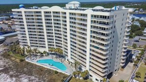 Un hotel a più piani con piscina, circondato da palme e vista sull'oceano.