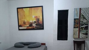 A bedroom with a bed, a chair, a window, and a painting on the wall. - CASA ALBINO, NICE HOUSE WITH 3 BEDROOMS, VERY COMFORTABLE AND CENTRALLY LOCATED. (Izamal)