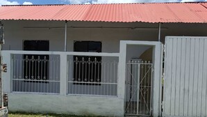 A building with a corrugated metal roof, a gated entrance, and a white exterior wall. - CASA ALBINO, NICE HOUSE WITH 3 BEDROOMS, VERY COMFORTABLE AND CENTRALLY LOCATED. (Izamal)