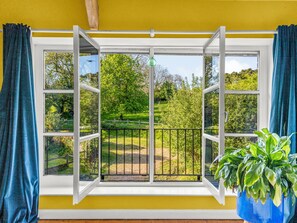 Ein Zimmer mit großem Fenster, einem Blumentopf und Blick auf eine grüne Landschaft.