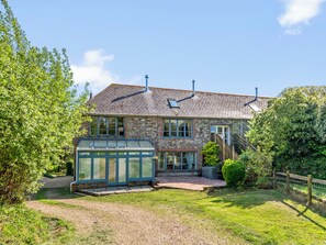 A two-story stone house with a conservatory, a wooden fence, and a gravel driveway. - Chantry (Kingsbridge)