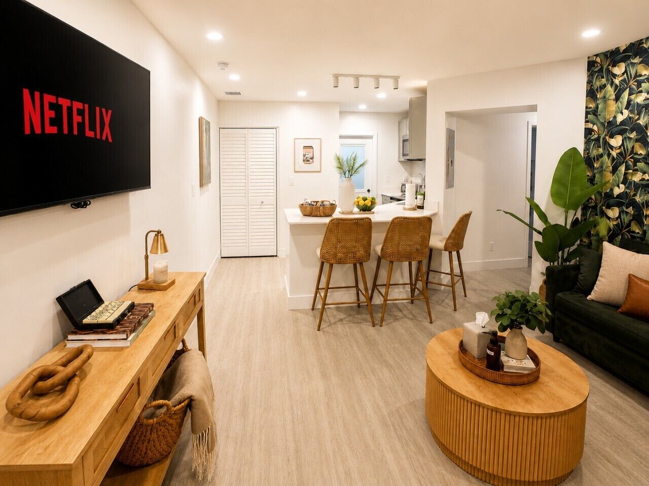 A modern living room with a flat-screen TV, a wooden coffee table, and a green sofa.