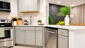 A modern kitchen with grey cabinets, a stainless steel stove, and a dishwasher. - Casa Tropica Escape | 2BR Near Beach & Airport (Dania Beach)