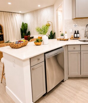 A modern kitchen with a dishwasher, a sink, and a countertop with various items. - 2BR Retreat Near FLL Airport, Beach & Cruise Port (Dania Beach)