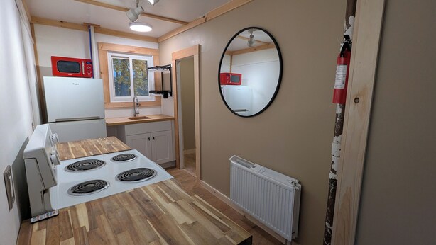 A compact kitchen with a stove, microwave, and refrigerator.