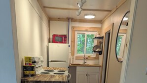 A compact kitchen with a wooden countertop, a white refrigerator, a microwave, and a sink.