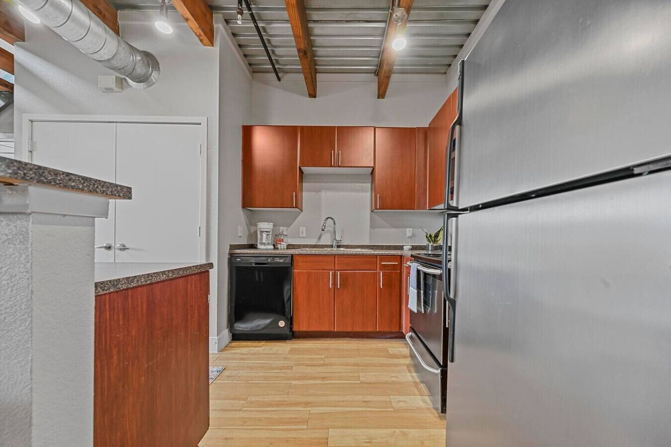 Une cuisine dotée de meubles en bois, d’un réfrigérateur en acier inoxydable, d’un lave-vaisselle et d’un four encastré.
