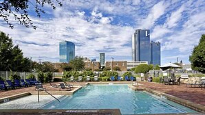 A swimming pool with lounge chairs, a brick deck, and a city skyline in the background. - Urban 3-bedroom loft - walk Downtown! (Fort Worth)