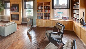 A spacious living room with a fireplace, a large bookshelf, and a view of the city through the windows. - Urban 3-bedroom loft - walk Downtown! (Fort Worth)