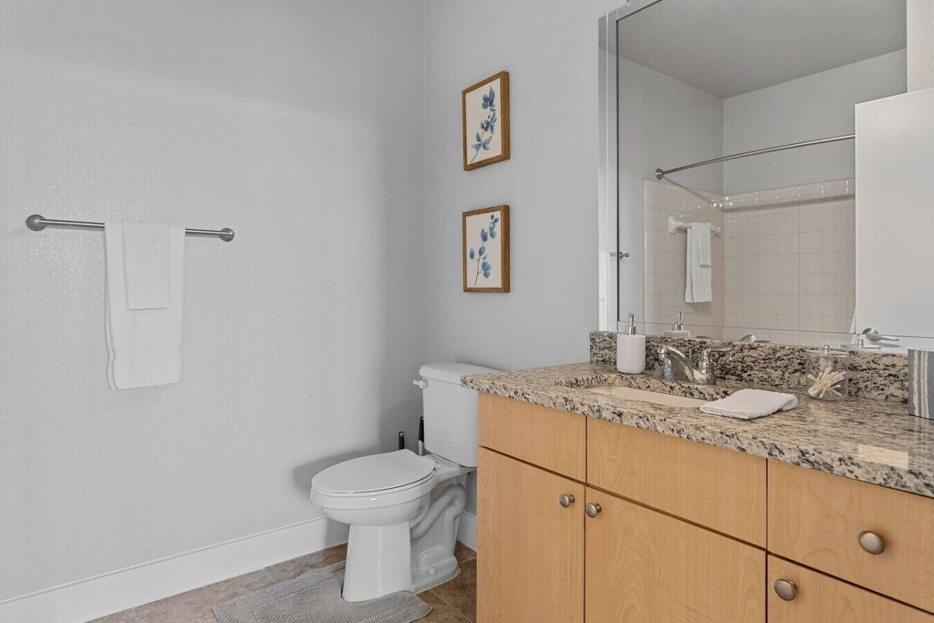 A bathroom with a toilet, vanity, sink, and mirror.