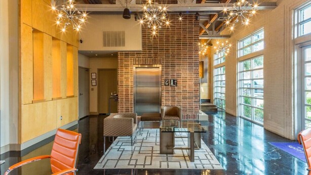 A spacious lobby with a modern design, featuring a glass table, leather chairs, and a brick accent wall. - Dive into downtown, steps away! (Fort Worth)