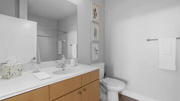 Un bagno moderno con doppio lavandino, un water e un grande specchio.