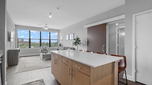 A modern kitchen with a large island, wooden cabinets, and a dining area with chairs.
