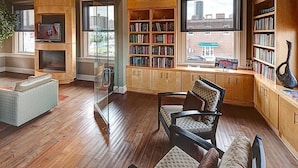 A spacious living room with a large bookshelf, a glass partition, and a view of the city.