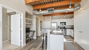 A modern kitchen with white cabinets, a central island, and a dining area. - Large Modern Loft — 3 Bedrooms, walk Downtown! (Fort Worth)
