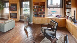 A spacious living room with a large bookshelf, a glass partition, and a view of the city. - Shop, dine, enjoy - walk Downtown! (Fort Worth)