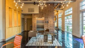 A spacious lobby with a modern design, featuring a glass coffee table, leather chairs, and a brick accent wall. - Relaxing Extended stays, walk Downtown! (Fort Worth)