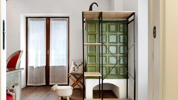 A room with a wooden floor, a green cabinet with shelves, a small white table, and a red chair. - Room 'Bed and Breakfast Pellizzano' (Pellizzano)