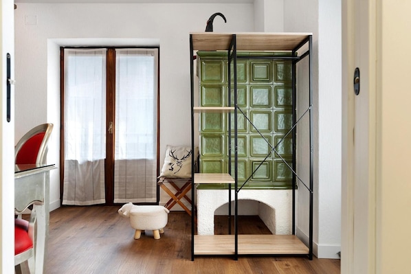 A room with a wooden floor, a green cabinet with shelves, a small white table, and a red chair.