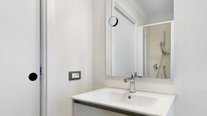 A bathroom with a white sink, a mirror, and a shower. - Room 'Bed and Breakfast Pellizzano' (Pellizzano)