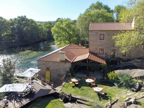 A stone building with a tiled roof, outdoor seating, and a river view. - Historic Riverside Mill Villa w/ Private Beach (Caminha)