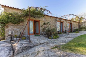 A stone building with a tiled roof, a stone patio, and a table with chairs. - River Beach Loft · Bob Dylan at the Watermill (Caminha)
